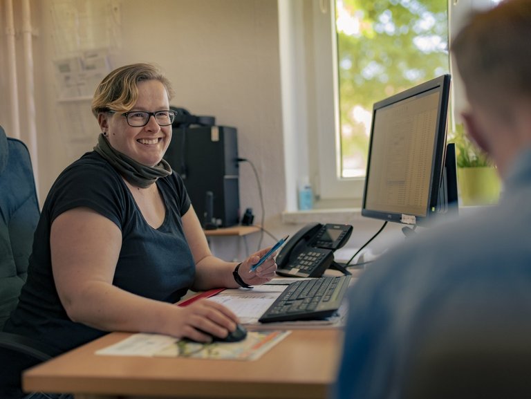 Zwei Personen die an einem PC sitzen und lachen. 