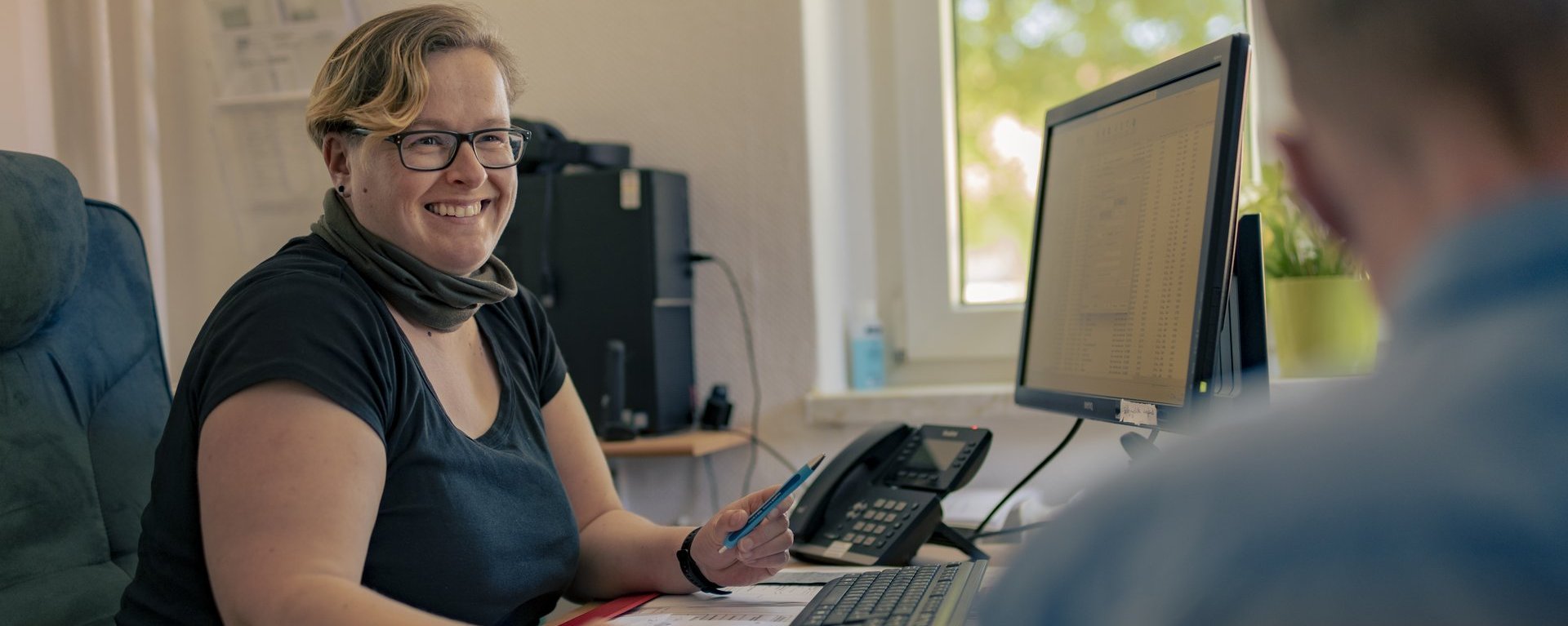 Zwei Person sitzen vor einem PC und unterhalten sich. 