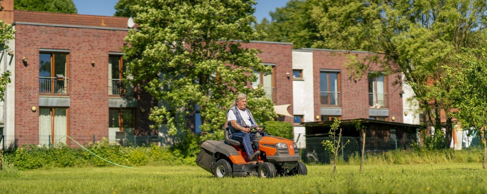 Eine Person sitzt auf einem Rasenmäher und mäht den Rasen.